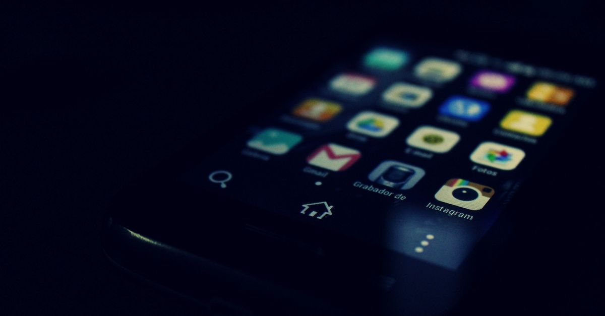 Smartphone avec une loupe symbolisant l'espionnage et la surveillance du téléphone