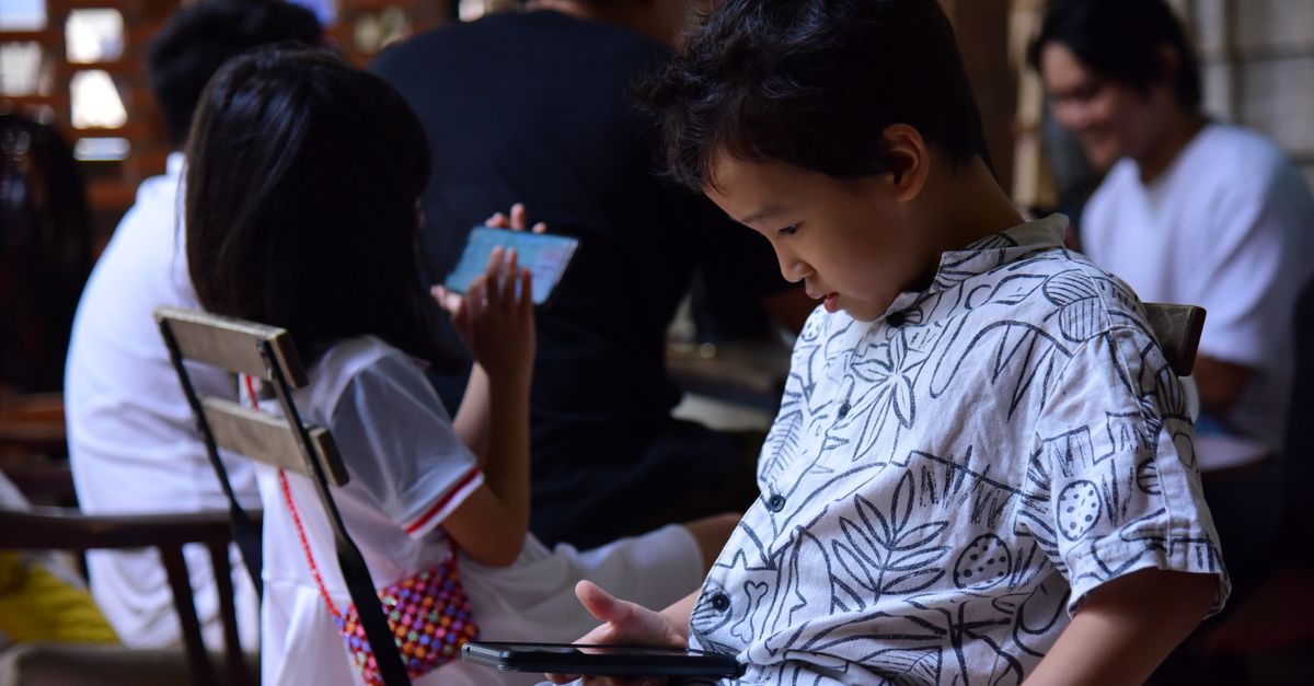 Enfant tenant un smartphone avec un parent qui guide la configuration