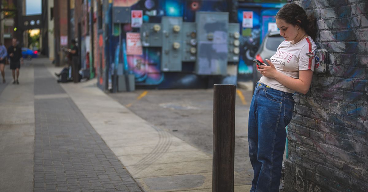 Mains tendues vers un smartphone posé sur une surface, représentant la récupération d'un appareil volé